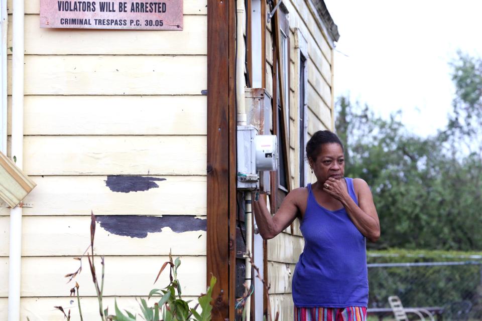 Beverly Perryman stands outside her home and watches as her nephew cuts down a tree with a machete in the Hillcrest neighborhood of Corpus Christi, TX on Saturday, August 26, 2017, the morning after Hurricane Harvey. She said, "The house got to shaking it tore the stuff off our roof."