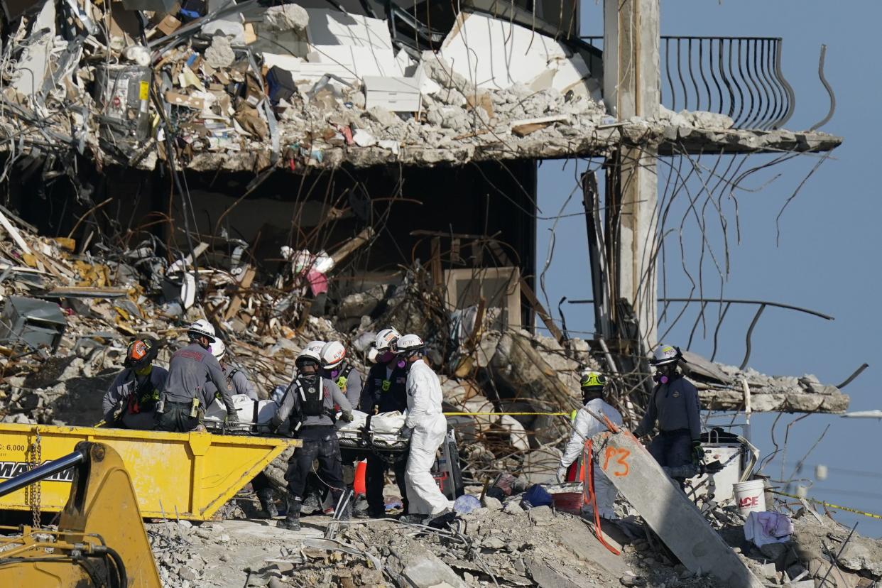 Search and rescue personnel remove remains on a stretcher as they work atop the rubble at the Champlain Towers South condo building where scores of people remain missing more than a week after it partially collapsed, Friday, July 2, 2021, in Surfside, Fla.