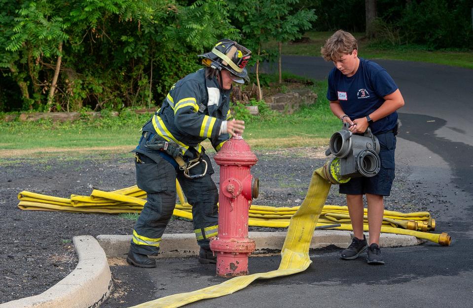 Lynn Kirkner, left, a firefighter with the Hartsville Fire Company, in Warminster, on Wednesday, July 27, 2022, assists Ian Woodson, 13, of Hatboro with the fire hydrant drill during the stationâ€™s firefighter camp for teenagers.