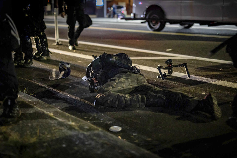 In this Aug. 5, 2020 photo, an activist who was filming protests lies on the street after being tackled by a police officer in Portland, Ore. His camera rig is seen on the ground nearby. Most police officers who violate citizens’ rights get away with it because the law is heavily stacked in their favor, legal experts say. (Maranie Rae Staab via AP)