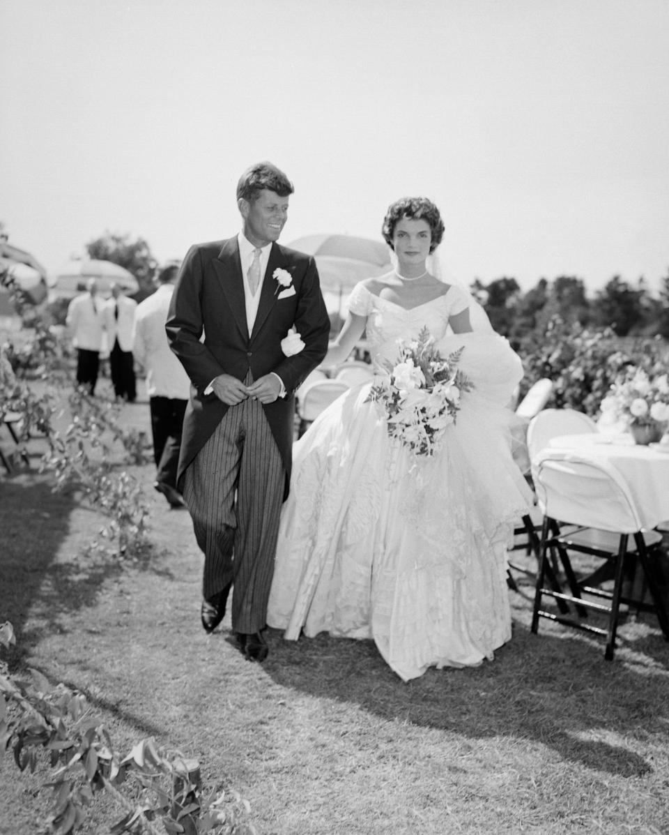 A scene from the Kennedy-Bouvier wedding. Groom John walks alongside his bride Jacqueline at an outdoor reception, 1953. Newport, Rhode Island. (Photo by Bachrach/Getty Images)