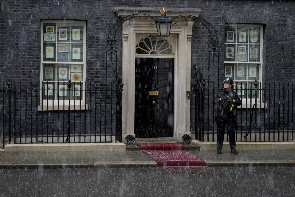 Hail falls during a thunder and lighting storm as a police officer stands guard outside 10 Downing Street in London, Tuesday, May 24, 2022. British Prime Minister Boris Johnson has been shadowed by career-threatening scandal for months — but so far he has escaped unscathed. This week he faces one more threat to his political future: a comprehensive report into coronavirus lockdown-breaching parties in government offices that is expected to be published within days. (AP Photo/Matt Dunham)