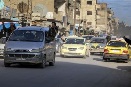 Fighters of the Kurdish People's Protection Units (YPG) carry their weapons along a street in the Syrian Kurdish city of Qamishli, in celebration after it was reported that Kurdish forces took control of the Syrian town of Tel Hamis, February 27, 2015. Kurdish forces dealt a blow to Islamic State by capturing an important town on Friday in the latest stage of a powerful offensive in northeast Syria, a Kurdish militia spokesman said. Islamic State has been forced into retreat across parts of the strategic region, a land bridge between territory it controls in Syria and Iraq, even as its fighters have mounted new raids this week on Assyrian Christian villages, abducting more than 200 people. REUTERS/Rodi Said