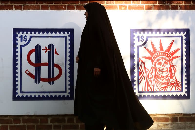 A woman walks past an Anti US mural on the former US embassy's wall in Tehran