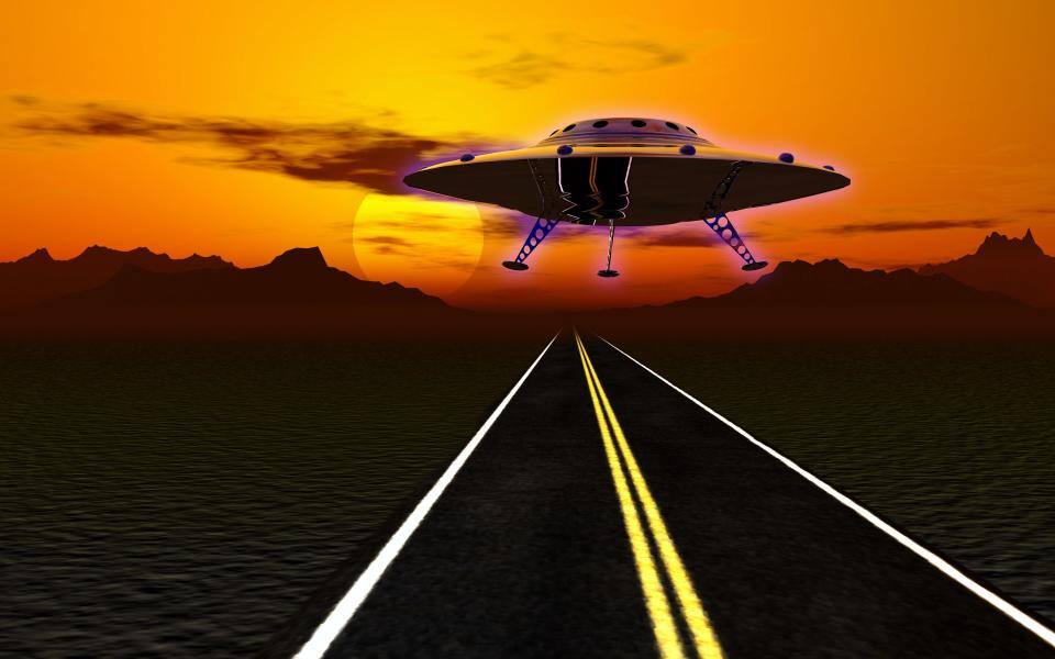 UFO flying over a desert road