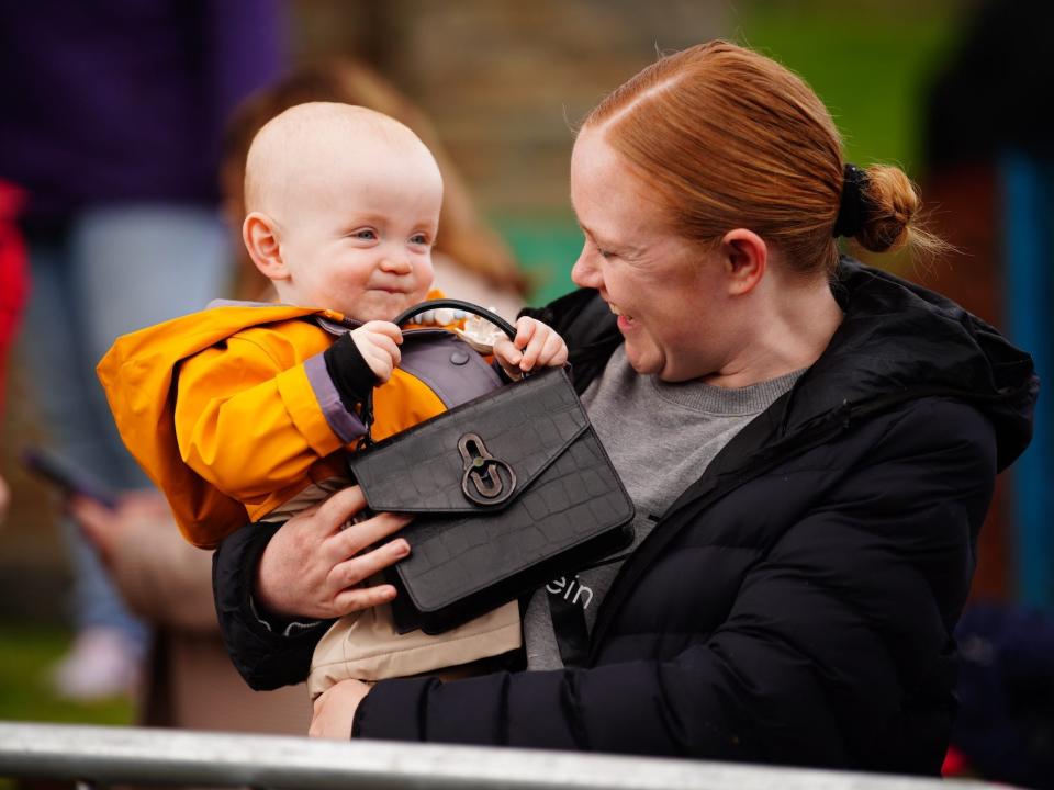 A woman and her baby hold Kate Middleton's purse.