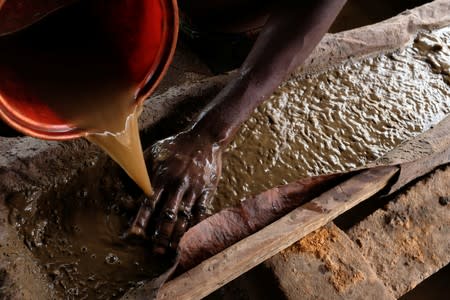 An informal gold miner pours water over ground-up rock at an angle to wash the heavier gold elements to the bottom at a site in Bawdie