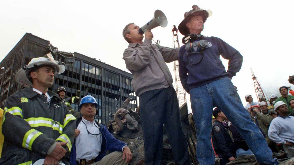 President George W. Bush addresses a crowd alongside retired firefighter Bob Beckwith at the remains of the World Trade Center collapse in September 2001. - Win McNamee/Reuters