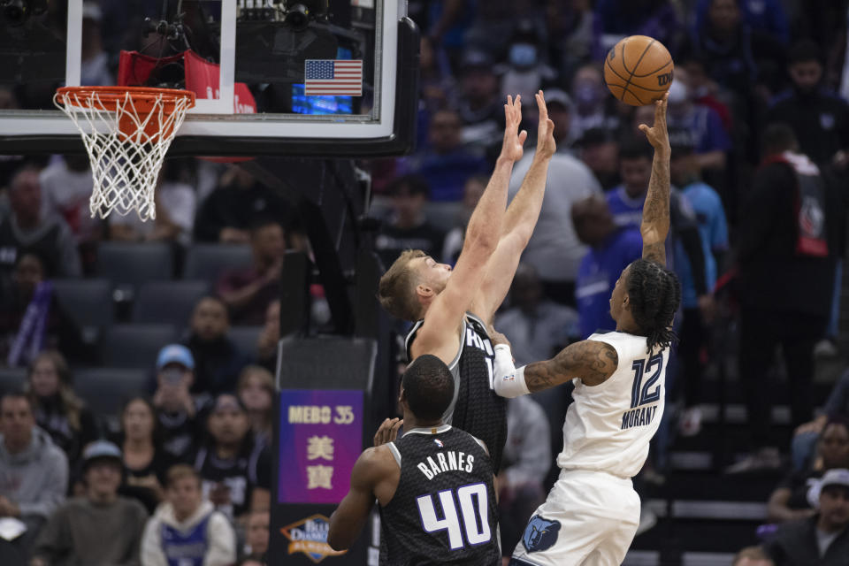 Memphis Grizzlies guard Ja Morant (12) scores over Sacramento Kings forward Domantas Sabonis (10) in the first quarter of an NBA basketball game in Sacramento, Calif., Thursday, Oct. 27, 2022. (AP Photo/José Luis Villegas)