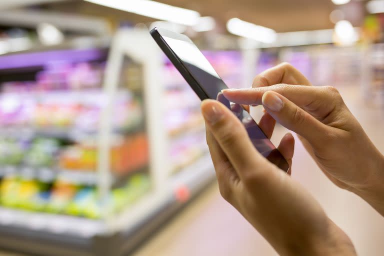 Woman using mobile phone while shopping in supermarket