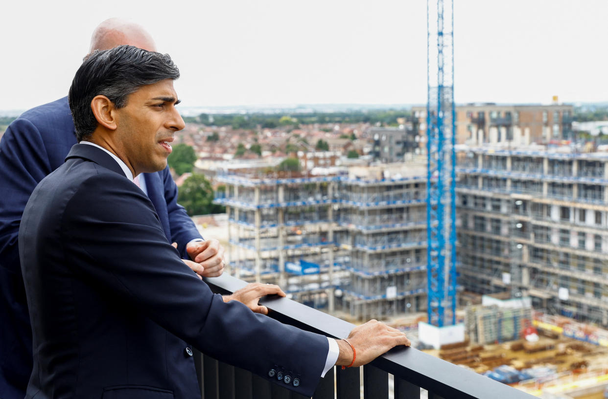 British Prime Minister Rishi Sunak talks with Barratt Developments regional managing director Gary Ennis on a balcony of a unit that is part of Hayes Village, a new housing development under construction by Barratt Homes on a brownfield site in London, Britain, July 27, 2023. REUTERS/Peter Cziborra/Pool