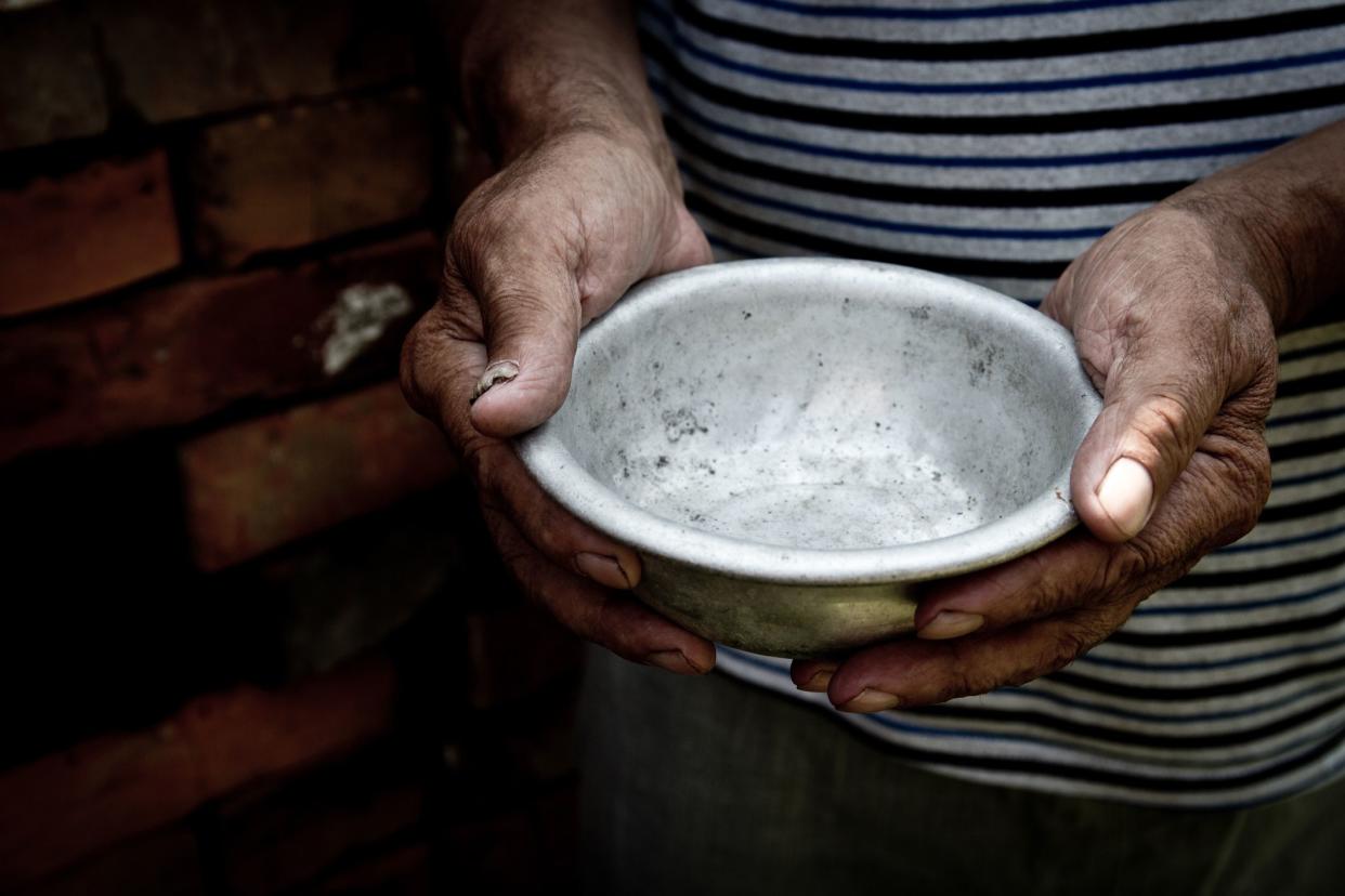 The poor old man's hands hold an empty bowl. The concept of hunger or poverty. Selective focus. Poverty in retirement.Homeless. Alms