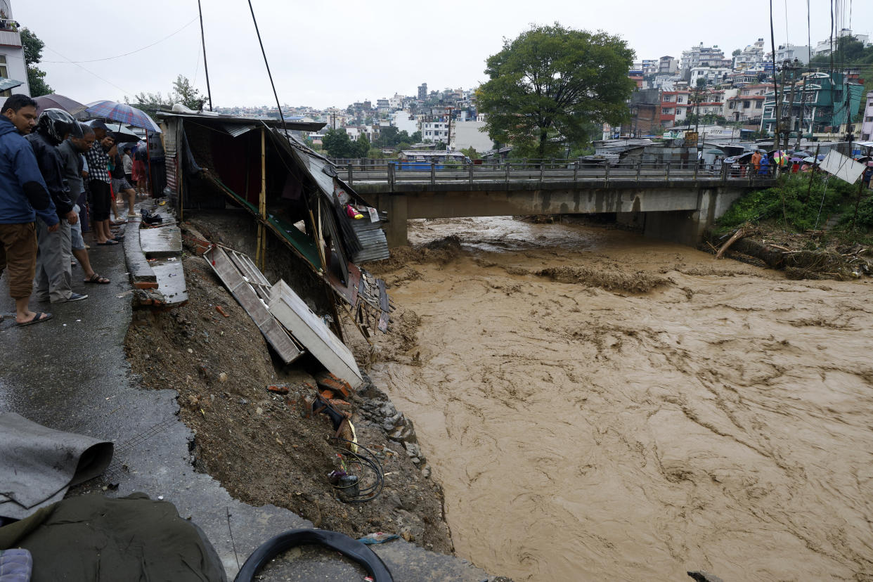 People gather at the edge of the Bagmati River in spate after heavy rains in Kathmandu, Nepal, Saturday, Sept. 28, 2024. (AP Photo/Gopen Rai)