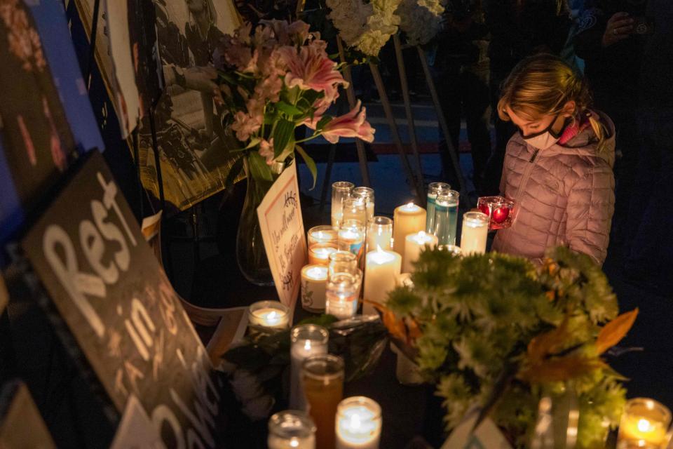 A girl pays respects near a photo of cinematographer Halyna Hutchins, who was accidentally killed by a prop gun fired by actor Alec Baldwin, at a memorial table during a candlelight vigil in her memory in Burbank, Calif., on Oct. 24. Authorities are continuing to investigate the shooting, which took place last month on the set of "Rust" in Santa Fe, N.M.