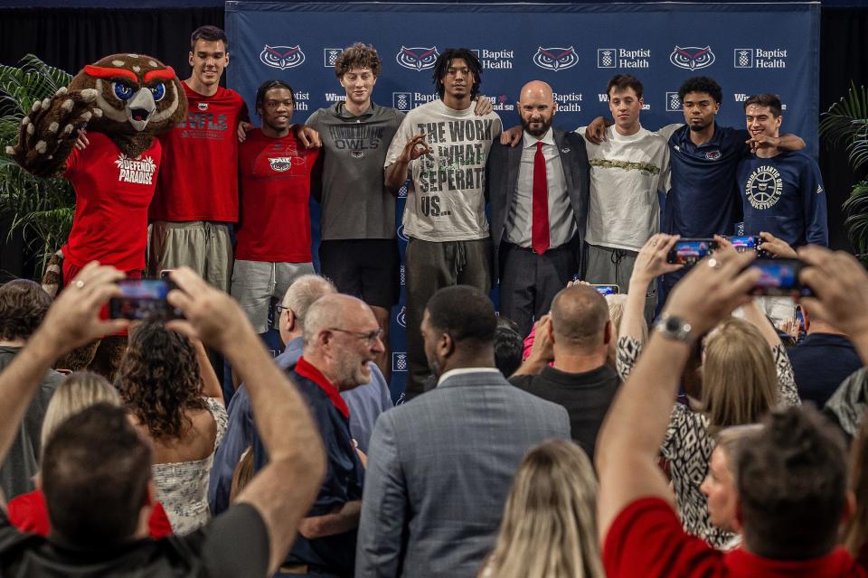 Florida Atlantic University men's basketball coach John Jakus, fourth from right, stands with his players Friday during a Florida Atlantic University news conference where he was introduced as the new men's baskerball coach.