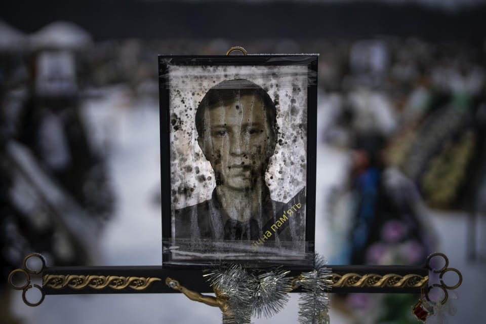 A worn-out portrait of Oleksandr Anatoliyovych, 43, sits on his grave at a cemetery in Irpin, Ukraine, on the outskirts of Kyiv, on Thursday, Feb. 9, 2023. He was buried on July 13, 2022. (AP Photo/Emilio Morenatti)