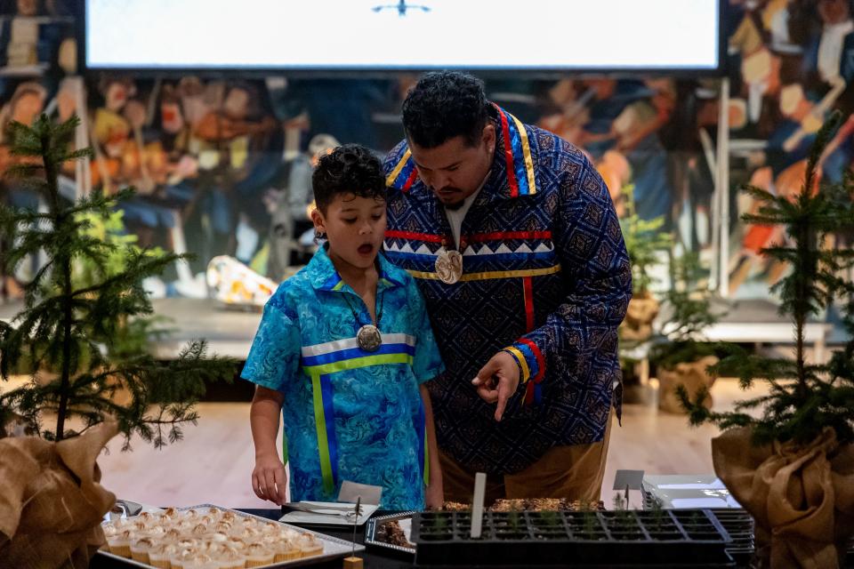 Little Coche Tiger with his father, Coche Tiger, look at a tray of red spruce saplings.