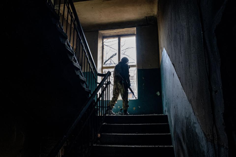 A Ukrainian serviceman looks through a broken window of a damaged residential building as the sounds of shelling continue in Bakhmut (AFP via Getty Images)