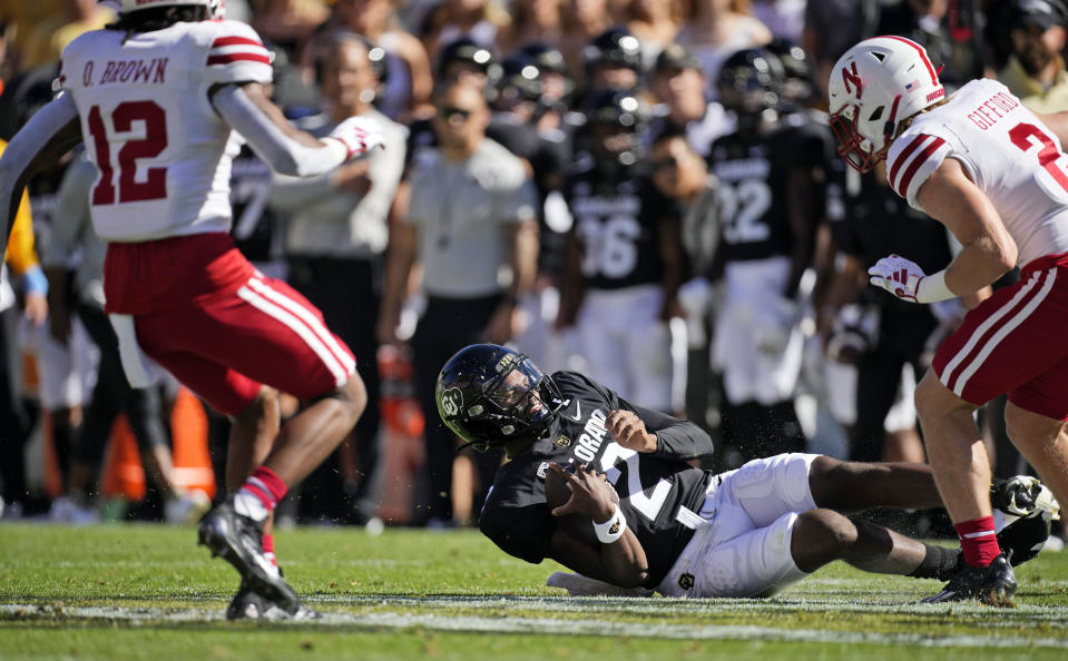 Colorado quarterback Shedeur Sanders, center, slides to avoid a tackle from Nebraska defensive back Isaac Gifford, right, as defensive back Omar Brown comes in to cover in the first half of an NCAA college football game Saturday, Sept. 9, 2023, in Boulder, Colo. (AP Photo/David Zalubowski)