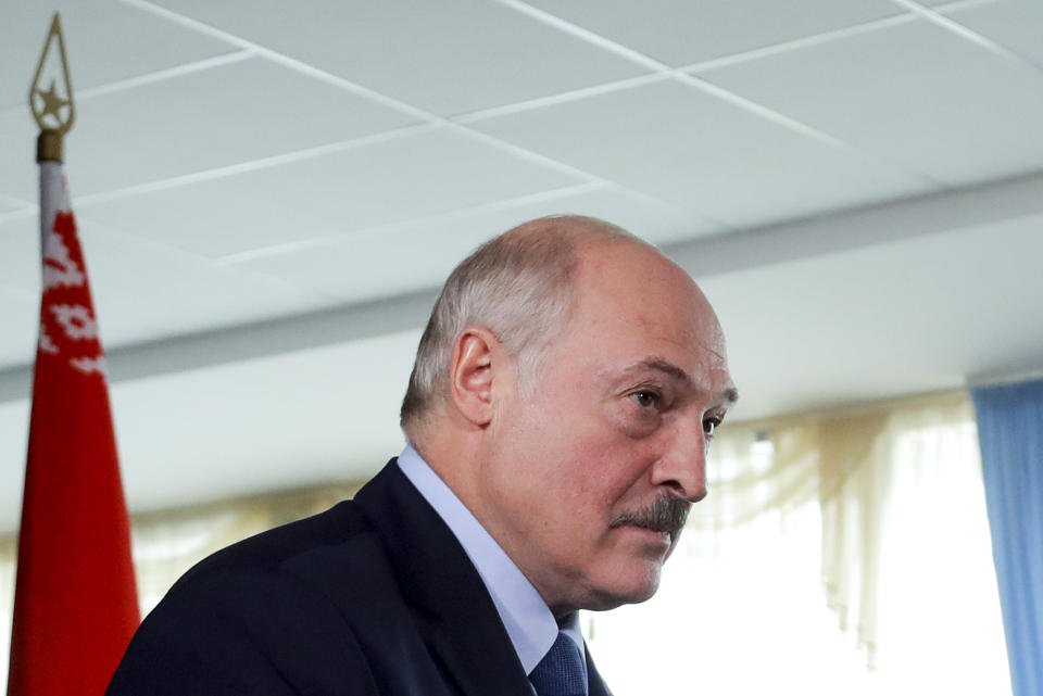 Belarusian President Alexander Lukashenko walks after voting at a polling station with a Belarusian national flag on the left, during the presidential election in Minsk, Belarus, Sunday, Aug. 9, 2020. Belarusians are voting on whether to grant incumbent president Alexander Lukashenko a sixth term in office, extending his 26-years rule, following a campaign marked by unusually strong demonstrations by opposition supporters. (AP Photo/Sergei Grits)