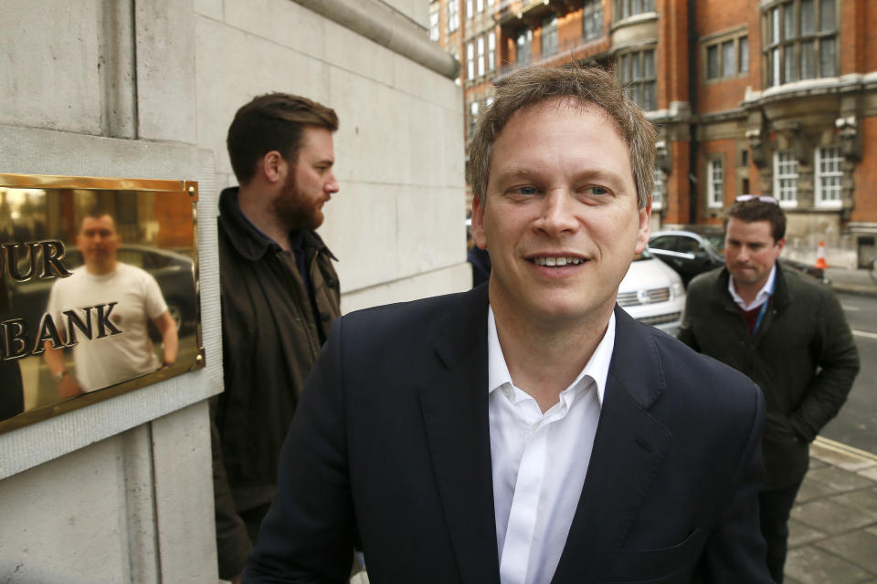 Dean Archer, a chauffeur and former local Labour Party councillor in Welwyn Hatfiled is reflected in a bronze plaque while he speaks to Conservative Party Chairman Grant Shapps as he arrives at television studios in central London, March 25, 2015.  REUTERS/Stefan Wermuth