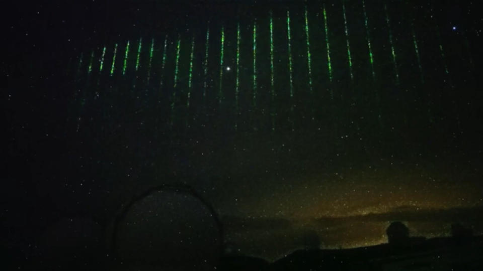 Lines of green light streak across the night sky