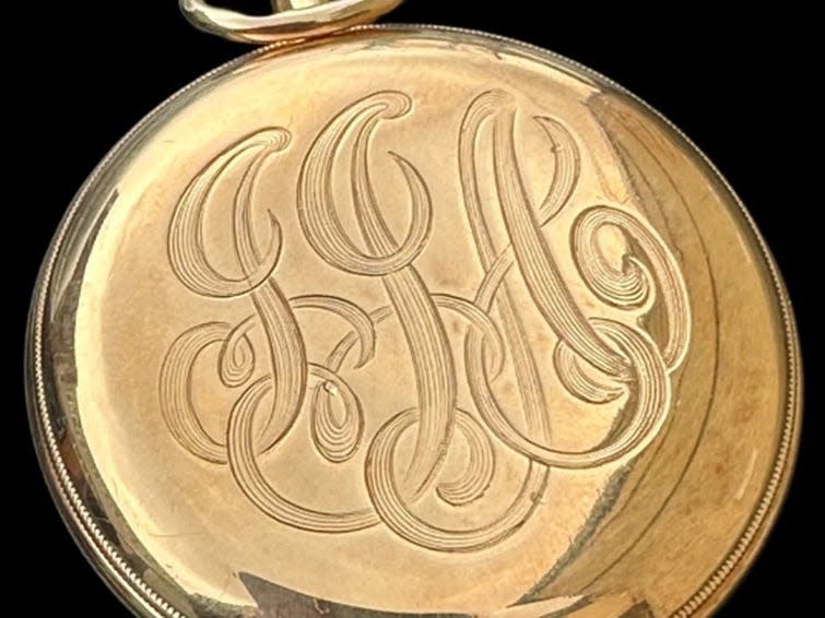 A closed gold pocket watch emblazoned with the initials JJA.