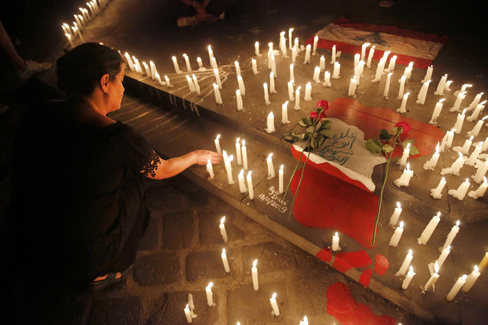 An anti-government protester lights candles at a makeshift memorial, during a vigil for Alaa Abu Fakher, who was killed by a Lebanese soldier during Tuesday night protests south of Beirut, at the Martyr square, in downtown Beirut, Lebanon, Wednesday, Nov. 13, 2019. (AP Photo/Hussein Malla)