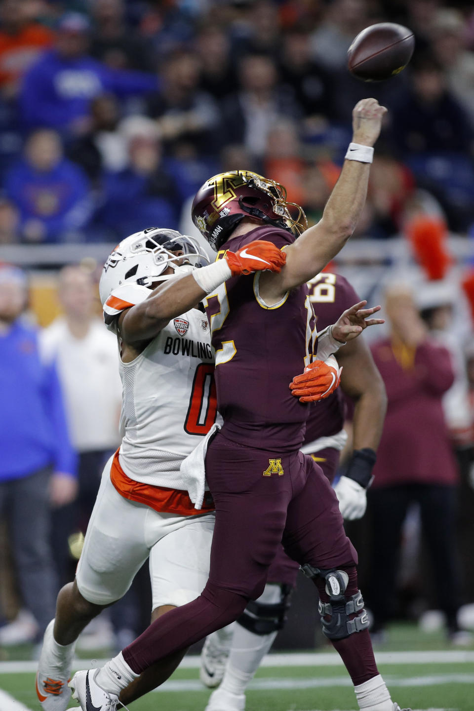 Bowling Green linebacker Cashius Howell (0), left, hits Minnesota quarterback Cole Kramer as he throws during the first half of the Quick Lane Bowl NCAA college football game, Tuesday, Dec. 26, 2023, in Detroit. The ball was intercepted by Bowling Green safety Darius Lorfils. (AP Photo/Al Goldis)