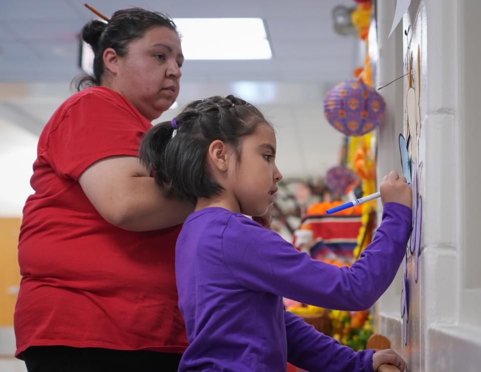 Sonia Salas helps her daughter, Alejandra, 6, decorate an ofrenda near the entrance at Capitol View Elementary School in Des Moines on Tuesday, Oct. 25, 2022.