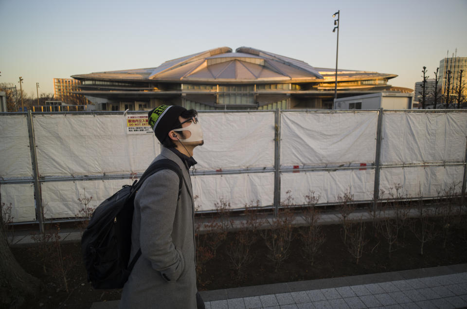 A man walks past the closed Tokyo Metropolitan Gymnasium, a venue renovated to be used in the rescheduled Tokyo Olympics, in Tokyo on Thursday, Jan. 21, 2021. The arena was used for the Tokyo 1964 Olympics. The postponed Tokyo Olympics are to open in just six months. Local organizers and the International Olympic Committee say they will go ahead on July 23. But it’s still unclear how this will happen with virus cases surging in Tokyo and elsewhere around the globe. (AP Photo/Hiro Komae)