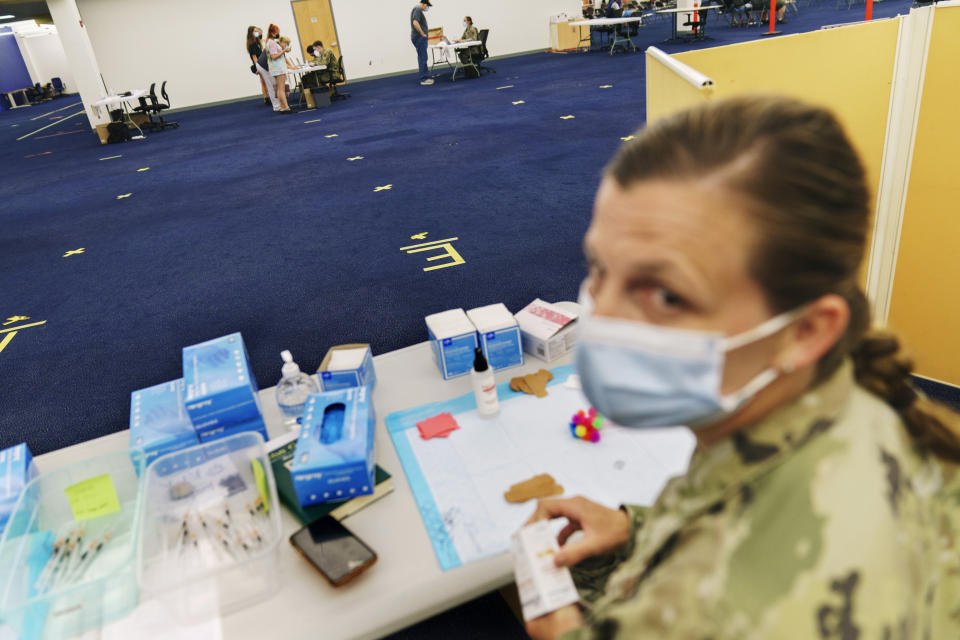 Tape on the floor marks where a line would normally form for people arriving for their COVID-19 inoculation as U.S. Air National Guard Capt. Jennifer Blake, right, waits for patients at a mass-vaccination site at the former Citizens Bank headquarters in Cranston, R.I., Thursday, June 10, 2021. The U.S. is confronted with an ever-growing surplus of COVID-19 vaccines, looming expiration dates and stubbornly lagging demand at a time when the developing world is clamoring for doses to stem a rise in infections. (AP Photo/David Goldman)