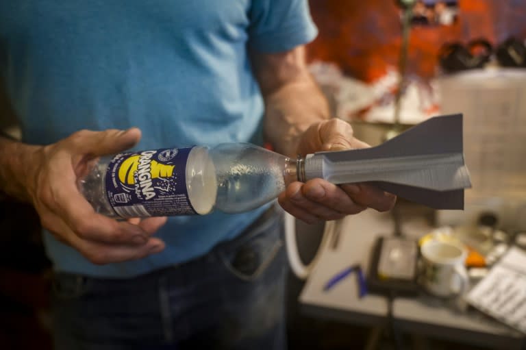 Un voluntario muestra una pieza de plástico para un cohete que imprimió en 3D en París, el 1 de junio de 2024 (Geoffroy VAN DER HASSELT)