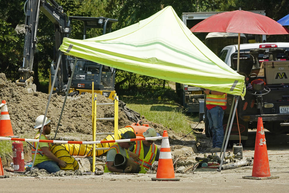 Utility workers use a series of umbrellas as they attempt to stay in the shade while working on a gas line in Jackson, Miss., Wednesday, June 28, 2023. (AP Photo/Rogelio V. Solis)