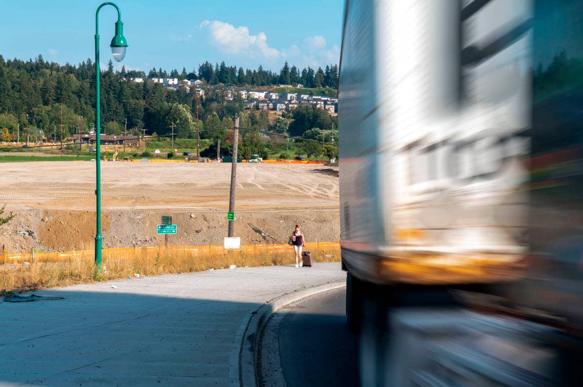 A woman walks along the sidewalk on Wapato Way East toward the bridge spanning Interstate 5 as truck traffic heads north on Wednesday, Aug. 31, 2022, in Fife. In the background work begins on diamond interchange for state Route 167 that will connect I-5 to state Route 509 Expressway.