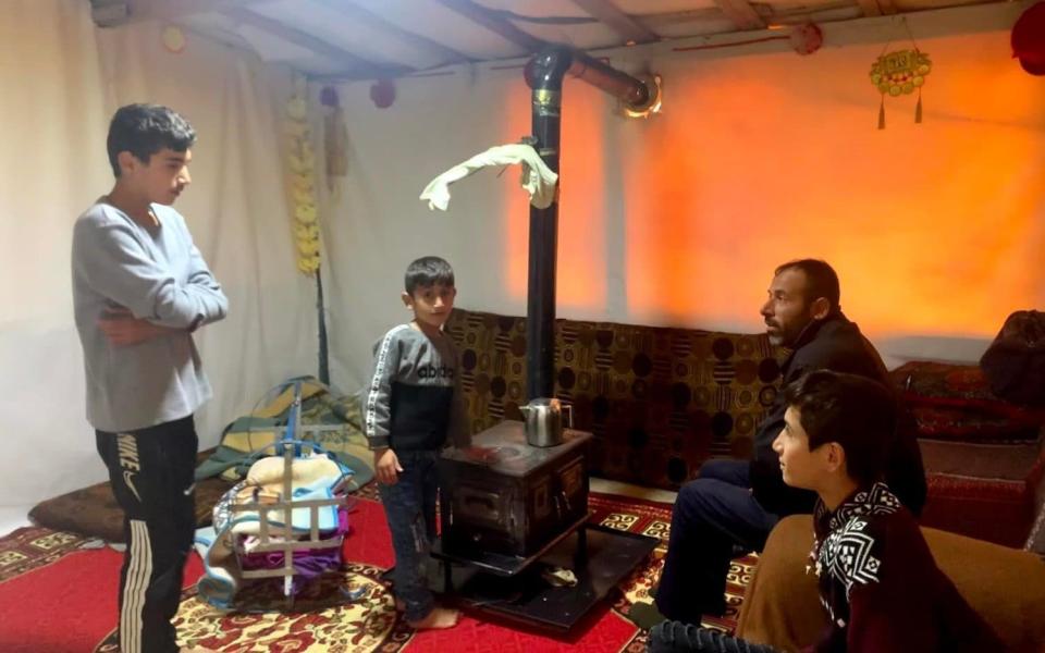 Nawaf and his faWinter is harsh for refugees such as Nawaf (standing) and his family who are huddled around the fire in their tentmily - Abbie Cheeseman