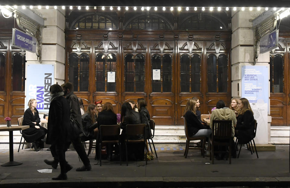 People take a drink outside a theatre on Saint Martin's Lane in central London, Saturday, Oct. 31, 2020. Earlier Saturday British Prime Minister Boris Johnson announced England will start a month long lockdown next week. Johnson says the new measures will begin Thursday and last until Dec. 2. (AP Photo/Alberto Pezzali, Pool)
