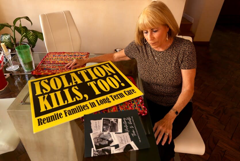 HERMOSA BEACH, CA - JANUARY 11, 2022 - - Karen Klink sits next to a sign she used in a protest when it was hard to visit her mother in a memory care facility during a three-month lockdown due to COVID-19 in late 2020. Klink wants to keep seeing her mother at the Redondo Beach facility where she lives and she needs to hand over a negative test for the virus before she is allowed to visit. She was photographed in her home in Hermosa Beach on January 11, 2022. In December, as coronavirus cases began to skyrocket with the spread of the highly contagious Omicron variant, California ordered nursing homes and other care facilities to require a negative test for COVID-19 for any visitors, even for outdoor visits. To meet the requirement, the test results must be fresh: Visitors must provide a negative result from a PCR test done within two days or an antigen test done within a single day, according to the state order. But many Californians are now facing long waits and sluggish turnaround times for PCR tests as demand has spiked. January 11: in Hermosa Beach on Tuesday, Jan. 11, 2022 in Hermosa Beach, CA. (Genaro Molina / Los Angeles Times)