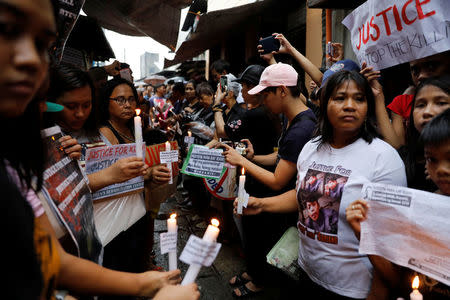 Protesters and residents hold lighted candles and placards at the wake of Kian Loyd delos Santos, a 17-year-old high school student, who was among the people shot dead last week in an escalation of President Rodrigo Duterte's war on drugs in Caloocan city, Metro Manila, Philippines August 21, 2017. REUTERS/Erik De Castro