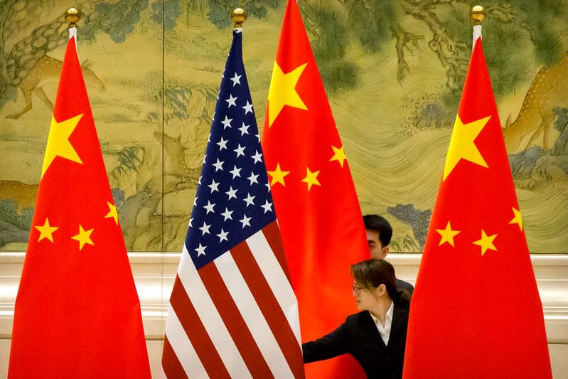 FILE PHOTO: Chinese staff members adjust U.S. and Chinese flags before the opening session of trade negotiations between U.S. and Chinese trade representatives in Beijing