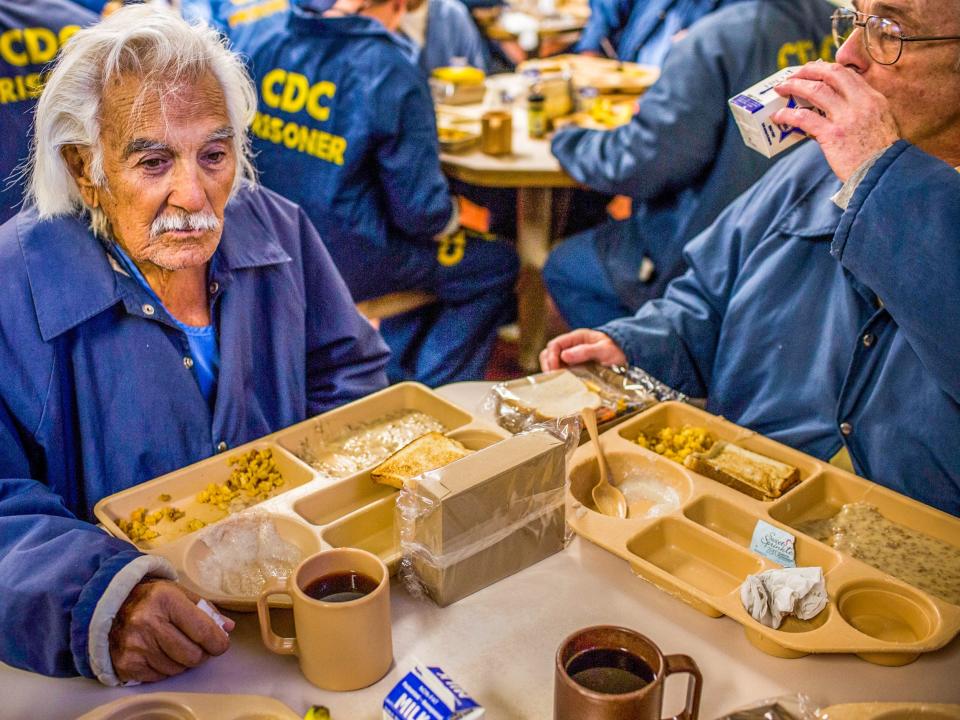 SAN LUIS OBISPO, CA - DECEMBER 19: (Editorial Use Only) Anthony Alvarez (L), age 82, eats breakfast with Phillip Burdick, a fellow prisoner and member of the Gold Coats program at California Men's Colony prison on December 19, 2013 in San Luis Obispo, California. The Gold Coats program is a volunteer care program where healthy prisoners volunteer to take care of elderly prisoners who either need general assistance with mobility and every day life or who also struggle with Alzheimer's and dementia. T(Photo by Andrew Burton/Getty Images)