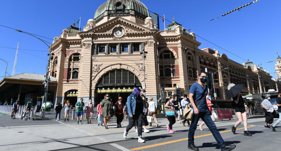 People wear masks while walking past Flinders Street station.
