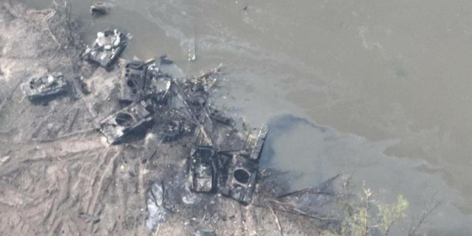 Destroyed military vehicles at the side of a river