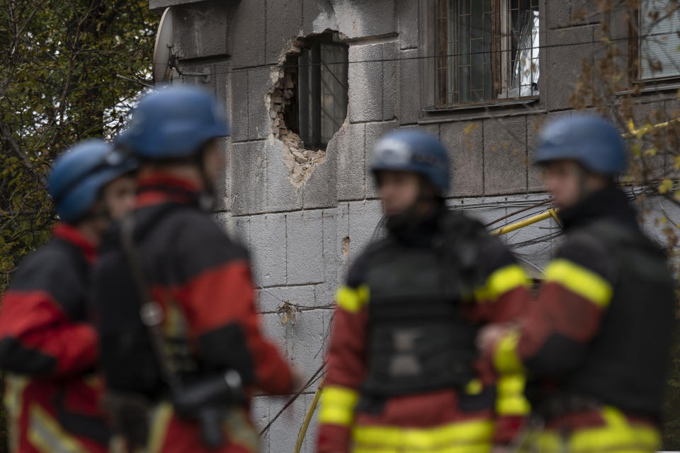 Firefighters stand next to a building that was damaged after a Russian attack in Zaporizhzhia, Ukraine, Friday, Oct. 21, 2022. (AP Photo/Leo Correa)