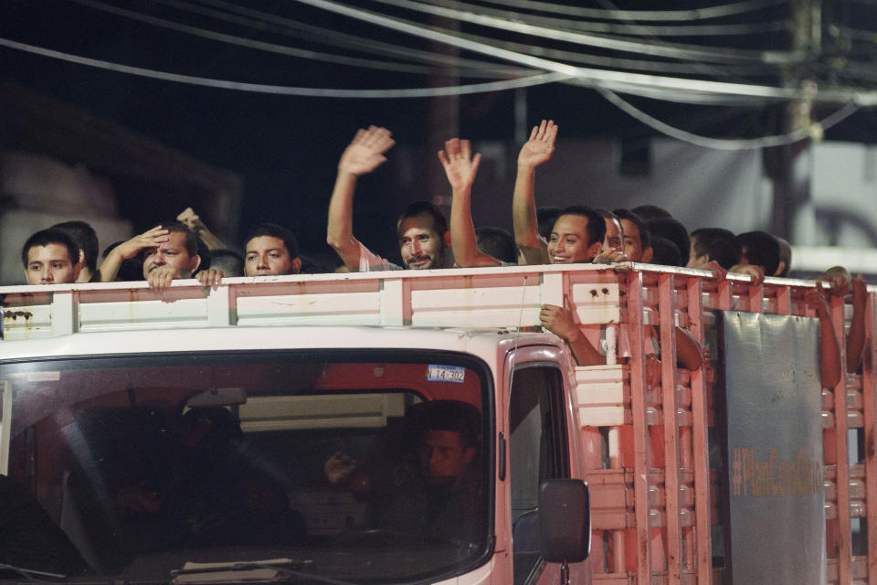 Men who were arrested under the ongoing "state of exception" wave at relatives from a cargo truck before their pending release, in San Salvador, El Salvador, late Friday, Oct. 14, 2022. With 55,000 people locked up since late March for alleged gang ties, El Salvador’s congress has approved another month-long extension of the state of exception that suspends some fundamental rights in the name of combatting the country’s powerful gangs. (AP Photo/Moises Castillo)