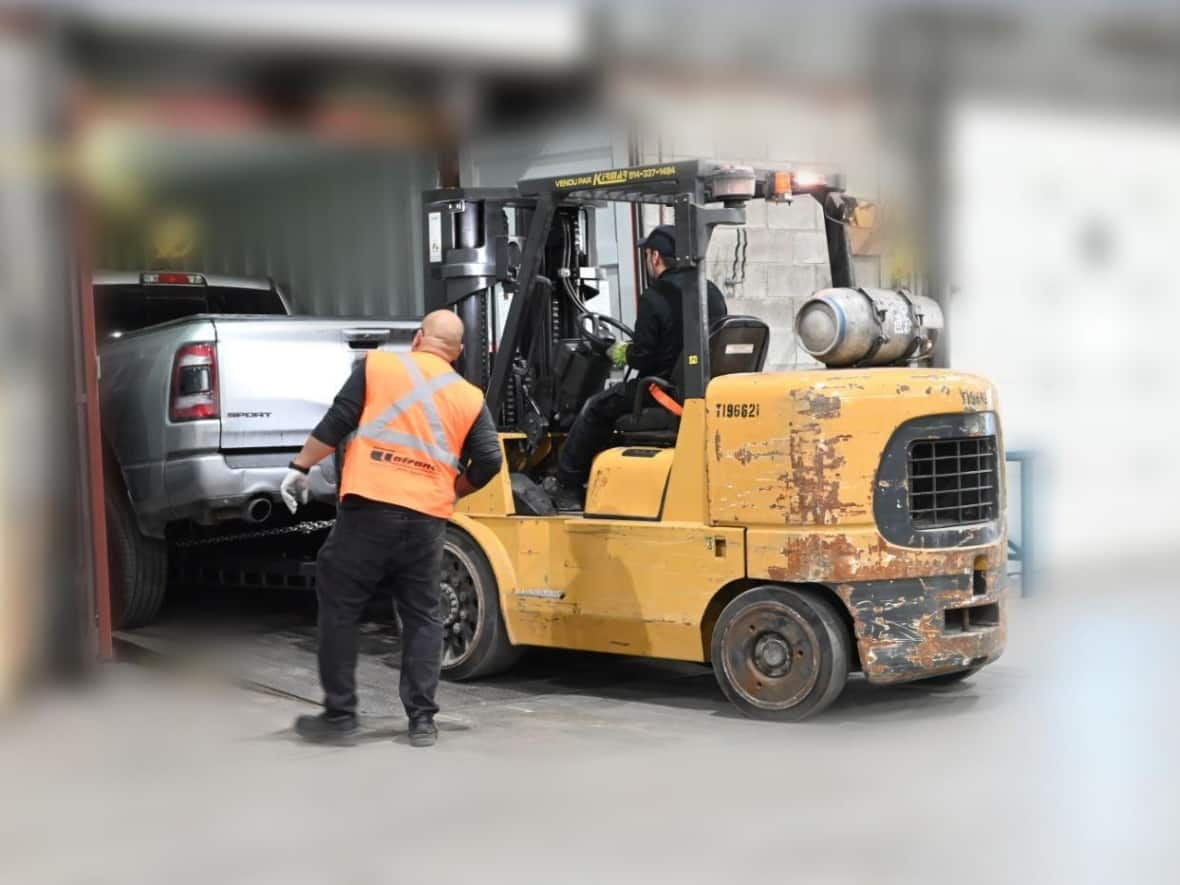 A pickup truck is seen being removed from a shipping container in this photo provided by Montreal police. The background has been blurred at the request of police to avoid being able to identify the location. (Service de Police de la Ville de Montréal - image credit)