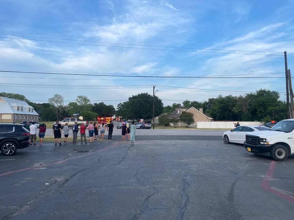 People gather across Denton Highway from the area where police were searching for an armed man following a shooting that killed two residents and injured four people, including three police officers, in Haltom City on Saturday, July 2, 2022.