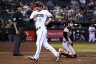 Arizona Diamondbacks' Carson Kelly (18) looks back after scoring a run as San Francisco Giants catcher Austin Wynns, right, and umpire Gabe Morales (47) pause at home plate during the fifth inning of a baseball game Tuesday, July 5, 2022, in Phoenix. (AP Photo/Ross D. Franklin)