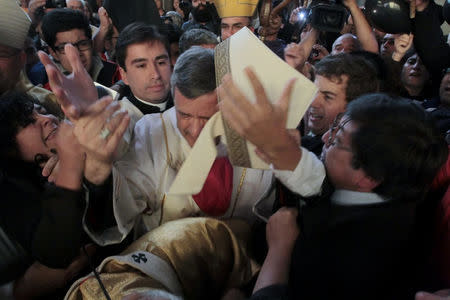 Bishop Juan Barros (C) attends his first religious service as citizens protest against him at the Osorno cathedral, south of Santiago, Chile March 21, 2015. REUTERS/Carlos Gutierrez