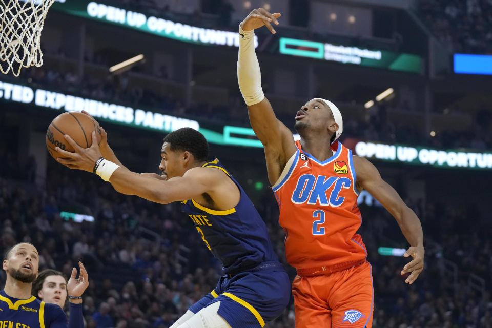 Golden State Warriors guard Jordan Poole, left, grabs a rebound next to Oklahoma City Thunder guard Shai Gilgeous-Alexander (2) during the first half of an NBA basketball game in San Francisco, Tuesday, April 4, 2023. (AP Photo/Jeff Chiu)